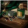 Perfume bottle labeled 'Serpentine Essence' with jewelry and a watch on a wooden surface.