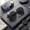Black sunglasses on a black book with a watch and keychain nearby