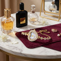 Luxury jewelry and perfume set on a marble surface with a mirror in the background.