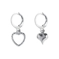 Silver hoop earrings with mismatched hanging heart charms, one solid and one open design
