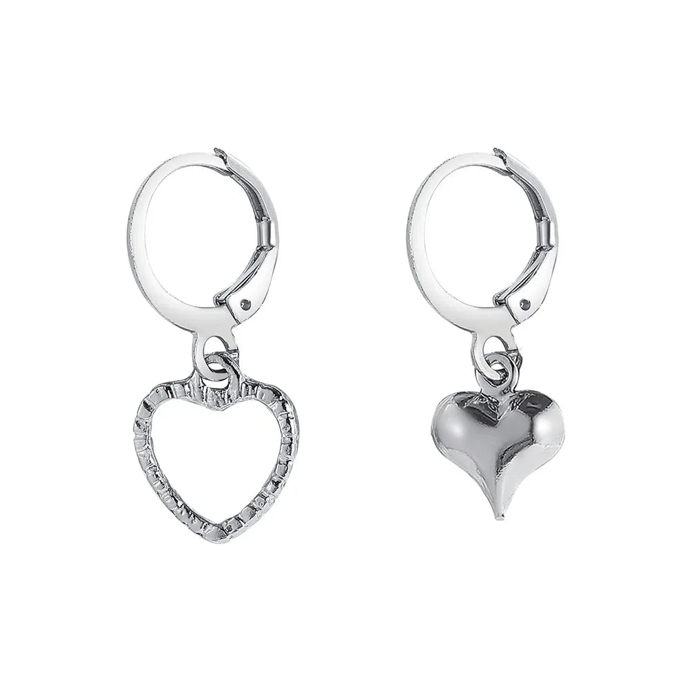 Silver hoop earrings with mismatched hanging heart charms, one solid and one open design