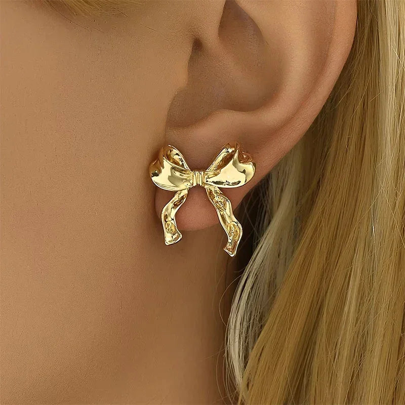 Gold bow-shaped stud earring on ear, elegant jewelry accessory for women