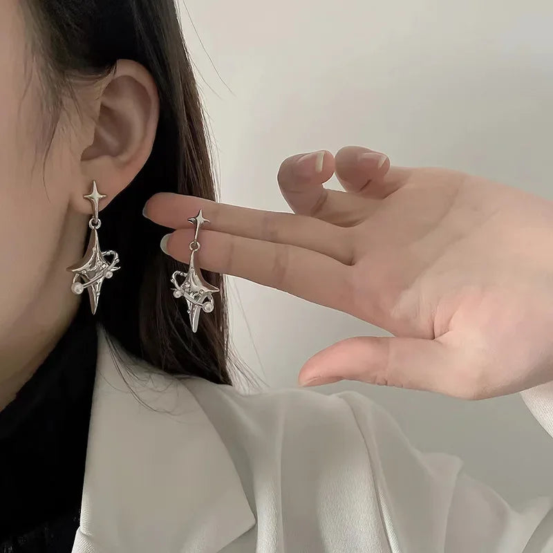 Close-up of woman wearing modern silver star and spike dangle earrings, contemporary jewelry