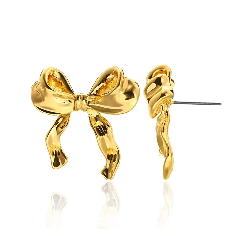 Gold bow-shaped stud earrings, modern designer jewelry on white background