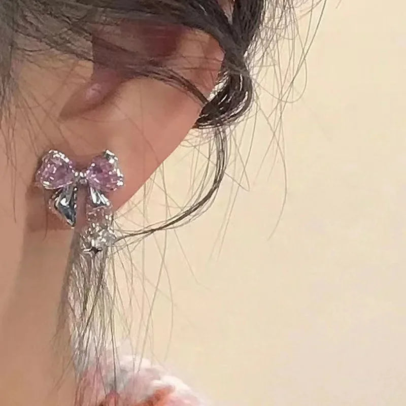 Elegant pink bow stud earring with crystal accents worn on ear, luxury jewelry style