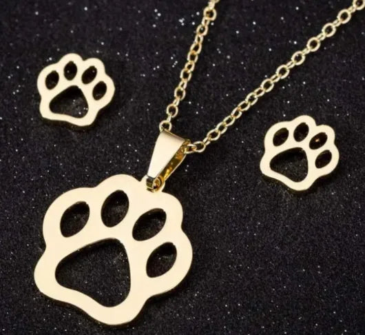 Gold paw print necklace and matching earrings on black textured background, pet jewelry set