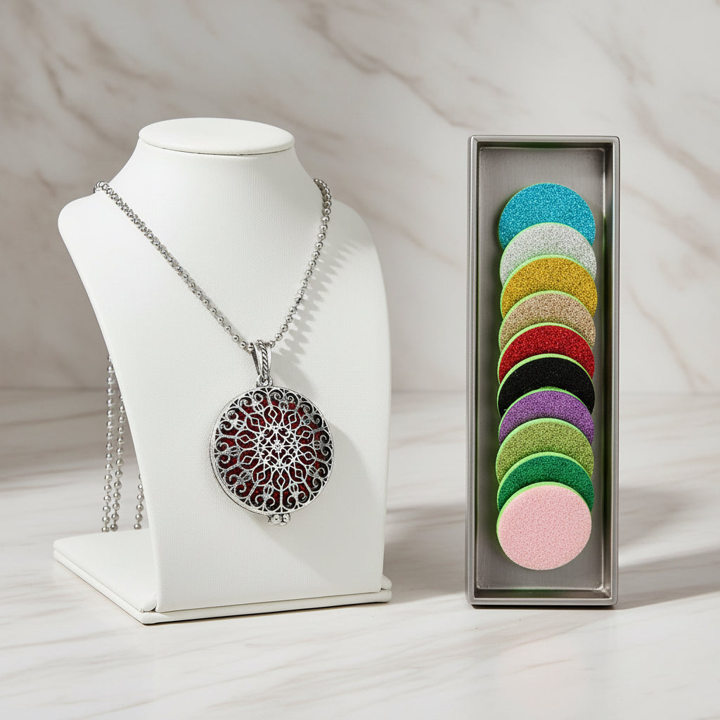 Silver necklace with a decorative pendant next to colorful round perfume pads on a white background.