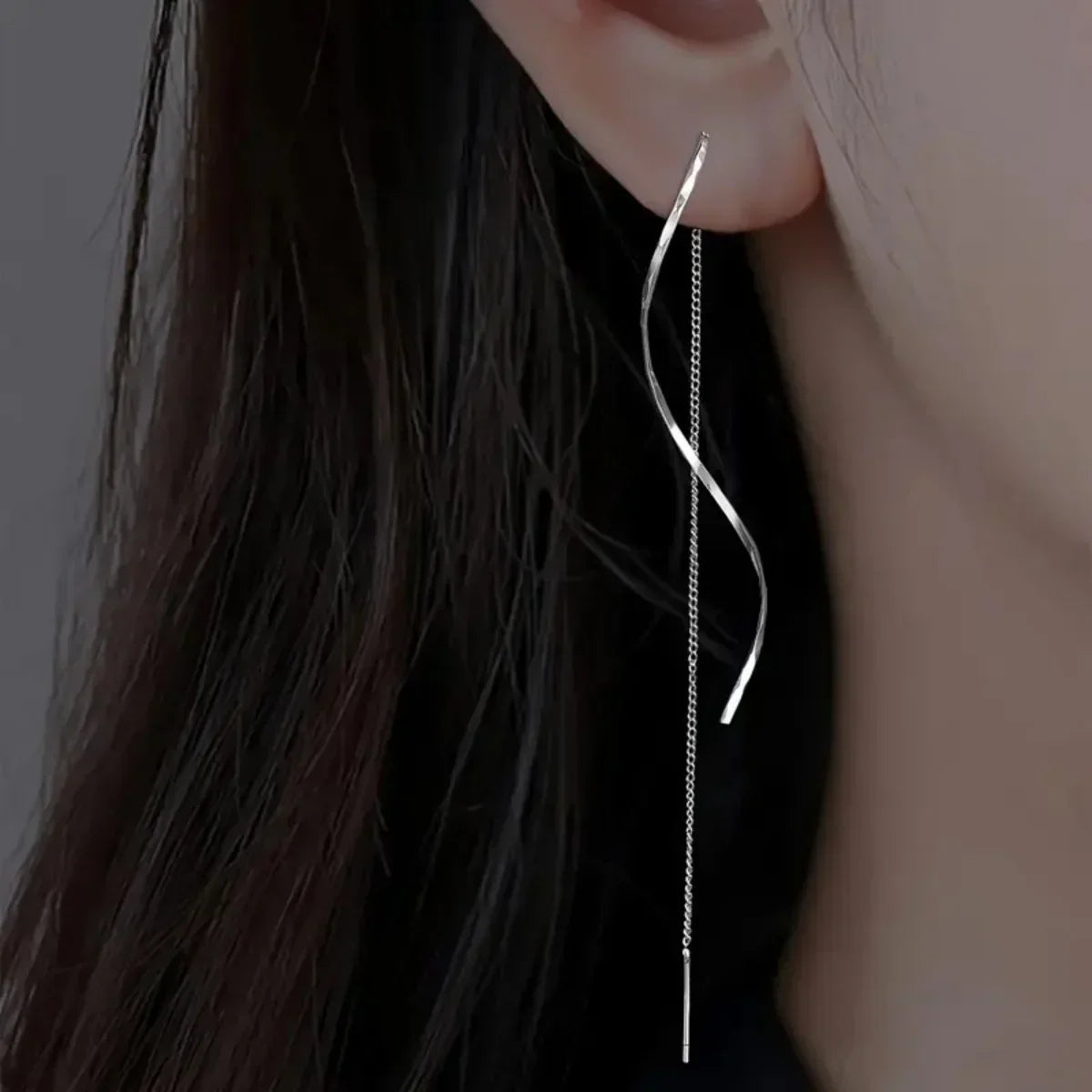 Elegant long silver threader earring with wavy design on woman's ear
