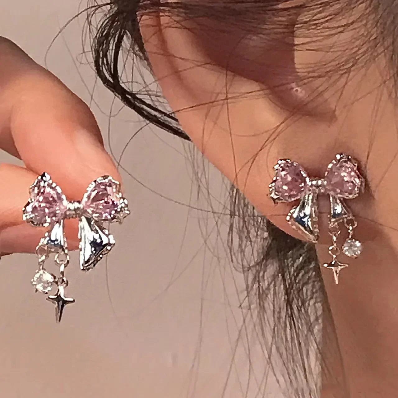Pink bow crystal earrings with dangling charms on ear, elegant and trendy jewelry style